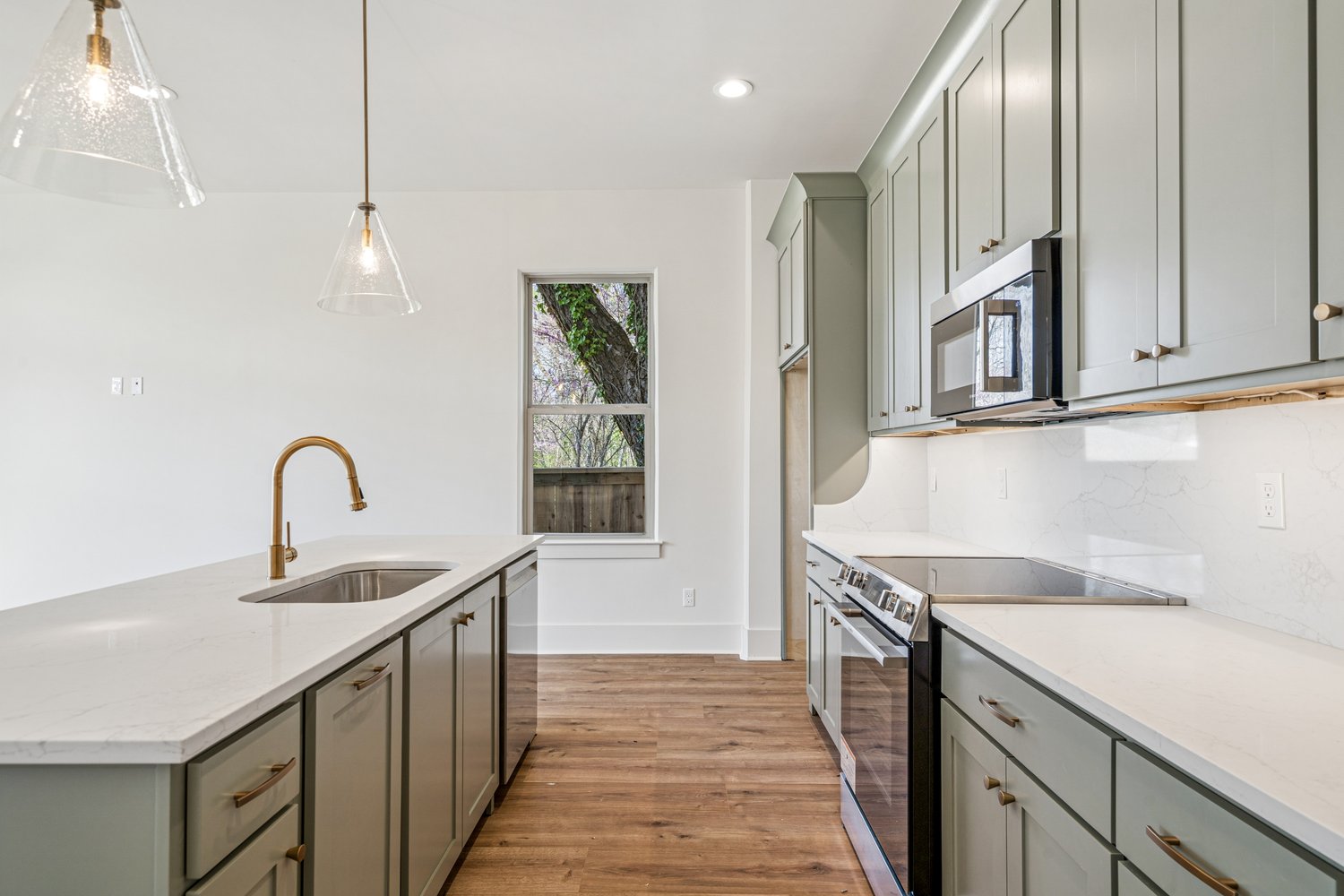 Chef's kitchen with sage cabinetry, quartz waterfall, and brass fixtures