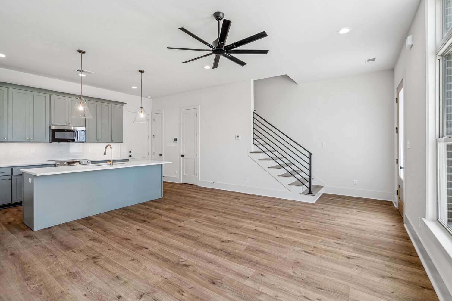 Open great room with light oak floors and floating stair